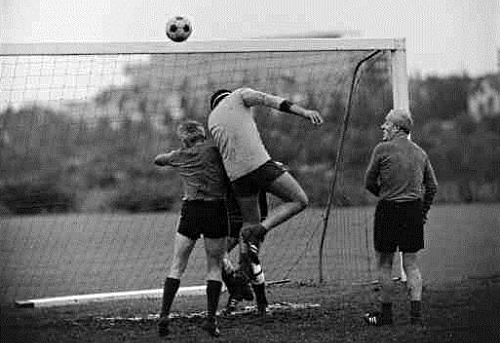Schwarz-Weiss Bild: Kopfball-Szene vor Tor.