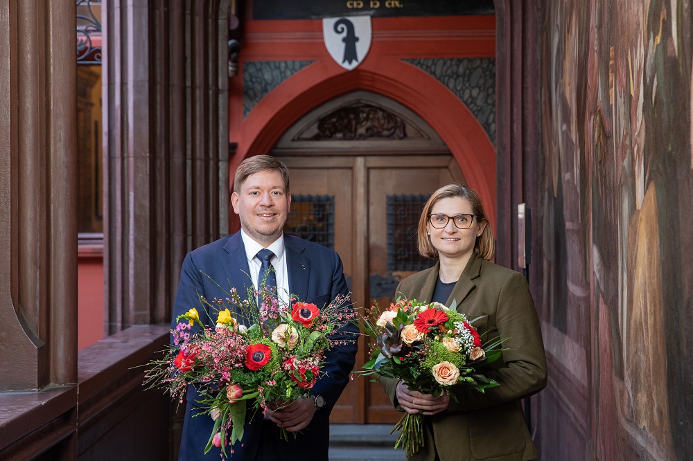 Balz Herter und Gianna Hablützel mit Blumensträussen vor der Eingangstüre ins Rathaus
