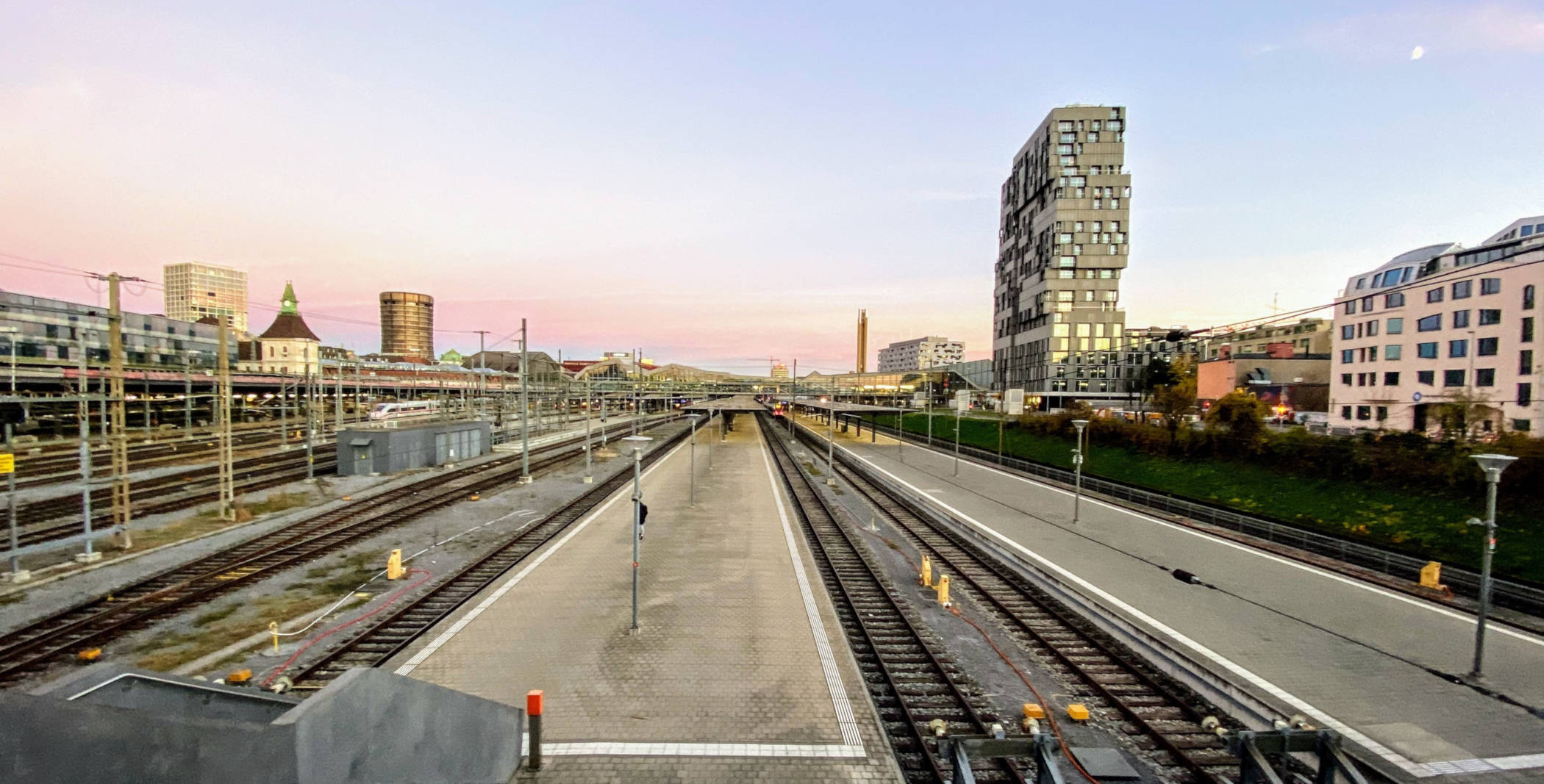 Gleise des Bahnhofs SBB und Meret Oppenheim-Hochhaus in der Abenddämmerung.
